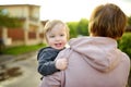 Cute funny toddler boy in his mothers arms. Mom and son having fun on sunny summer day in a park. Adorable son being held by mommy Royalty Free Stock Photo