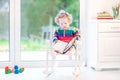 Cute funny toddler girl reading in rocking chair Royalty Free Stock Photo