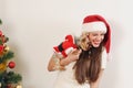 Cute funny woman in Santa hat with toy terrier near Christmas tr Royalty Free Stock Photo