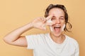 Cute funny woman wearing white T-shirt with hydrogel patches under eyes and shampoo foam on her head isolated over beige Royalty Free Stock Photo