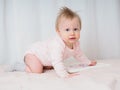 Cute gentle baby girl, 10 months old, crawling, looking surprised at the camera, close-up. Portrait of a girl in pink tones. Baby Royalty Free Stock Photo