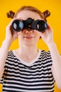 Cute ginger woman in a striped dress looking in binoculars. Close up Royalty Free Stock Photo