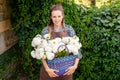 A cute girl in an apron with a basket of white dahlias flowers is standing near a vineyard Royalty Free Stock Photo