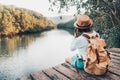 girl backpacking and sitting on the wood plank resting and looking on the river