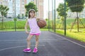 Cute girl with a basketball ball on the playground. Healthy lifestyle and sport concepts
