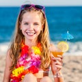 Cute girl on beach holding fruit cocktail.