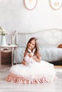 Cute girl in a beautiful white dress sits with a toy in a light room. Vertical. happy childhood Royalty Free Stock Photo