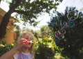 Cute girl blowing soap bubbles outdoor at summer park Royalty Free Stock Photo