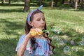 Cute girl in blue dress blowing soap bubbles in summer in the Park. Royalty Free Stock Photo