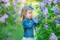 Cute girl in blue jackets with fairy airy skirt standing close to lilac bush Royalty Free Stock Photo