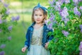 Cute girl in blue jackets with fairy airy skirt standing close to lilac bush Royalty Free Stock Photo