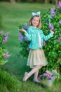 Cute girl in blue jackets with fairy airy skirt standing close to lilac bush Royalty Free Stock Photo