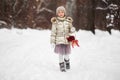 Cute girl with bouquet of flowers in a basket in a winter snowy day in the forest.