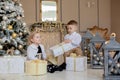 Cute Girl and boy opening Xmas presents. Children under Christmas tree with gift boxes. Decorated living room with traditional Royalty Free Stock Photo