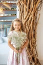 Cute girl, Caucasian, blond hair and pink pastel dress with a bouquet of gypsophila flowers. Royalty Free Stock Photo