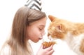 Cute girl celebrates holiday with cake and red cat. Royalty Free Stock Photo