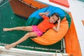 Cute girl at chair-bag on catamaran`s hammock.