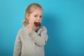 Cute girl child eating sweet chocolate candy on blue background. Happy childhood Royalty Free Stock Photo