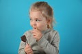 Cute girl child eating sweet chocolate candy on blue background. Happy childhood Royalty Free Stock Photo