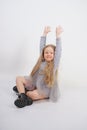 Cute girl child with long blond hair sitting on the floor and yawns sweetly, stretching her hands in different directions on white Royalty Free Stock Photo