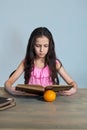 Cute girl-child sitting with books, reading fiction. Learning at home