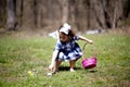 Cute girl collecting the colorful easter eggs from the ground with a pink basket Royalty Free Stock Photo