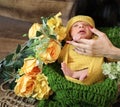 Cute girl covered with yellow blanket and head scarf lying on green knit textile yellow flowers