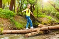 Cute girl crossing the river in summer forest Royalty Free Stock Photo