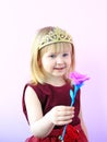 Cute girl with crown on head offering pink rose.Child in beautiful dress smiling Royalty Free Stock Photo