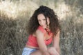 Cute girl with curly hairs sitting on the dry grass Royalty Free Stock Photo