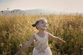 Cute girl dancing through a beautiful meadow with wheat and flowers in the mountains Royalty Free Stock Photo