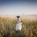 Cute girl dancing through a beautiful meadow with wheat and flowers in the mountains Royalty Free Stock Photo