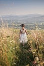 Cute girl dancing through a beautiful meadow with wheat and flowers in the mountains Royalty Free Stock Photo