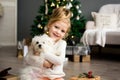 Beautiful girl with dog sitting near the Christmas tree. Merry Christmas and Happy Holidays. Royalty Free Stock Photo