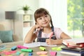 Cute girl doing homework at table with school stationery Royalty Free Stock Photo