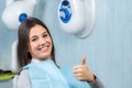 Cute girl doing thumbs up in dental clinic.