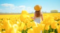 Cute girl in dress and straw hat walking in the field of yellow tulips windmill in the background. Blue sky sunlight summer day Royalty Free Stock Photo