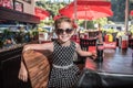 Cute girl drinking a coca cola a 50`s style restaurant with sunglasses