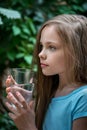 Cute girl drinking water. Little young lady holds glass of clean mineral water