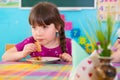 Cute girl eating baked apple in kindergarten