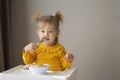 Cute girl eating healthy food with a spoon at home