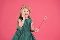 Cute girl in fairy dress and golden crown holding magic wand on pink background. Little princess Royalty Free Stock Photo