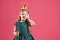 Cute girl in fairy dress with golden crown and magic wand on pink background, space for text. Little princess Royalty Free Stock Photo