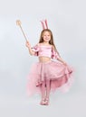 Cute girl in fairy dress with pink crown and magic wand on light grey background. Little princess Royalty Free Stock Photo