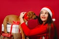 A cute girl with favorite puppy on the holiday boxes. Red background, holidays