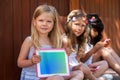 Cute girl with friends showing blank tablet. Royalty Free Stock Photo