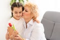 Cute girl giving a flower to her grandmother. Happy senior grandma hugging granddaughter thanking for flower. Girl Royalty Free Stock Photo