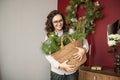 A cute girl with glasses holds a basket of nobilis near the red wall