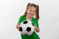 A cute girl in a green t-shirt with a soccer ball in her hand smiles isolated on a white background. A sporty caucasian kid holds Royalty Free Stock Photo