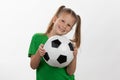 A cute girl in a green t-shirt with a soccer ball in her hand smiles isolated on a white background. A sporty caucasian kid holds Royalty Free Stock Photo